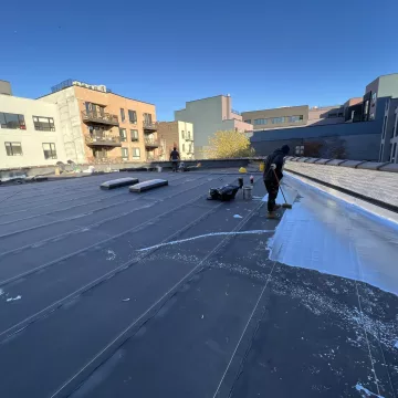 The_skilled_labourer_of_The_Premium_Roofing_is_meticulously_applying_the_protective_coating_on_the_roof_using_a_roller,_ensuring_durability_and_longevity_for_the_structure_in_Brooklyn_New_York